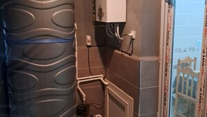A room with a large water tank, a white heater, and a window with blinds. - Rental per night in Tlemcen - imama Mansourah Appartement F4 neuf (Tlemcen)