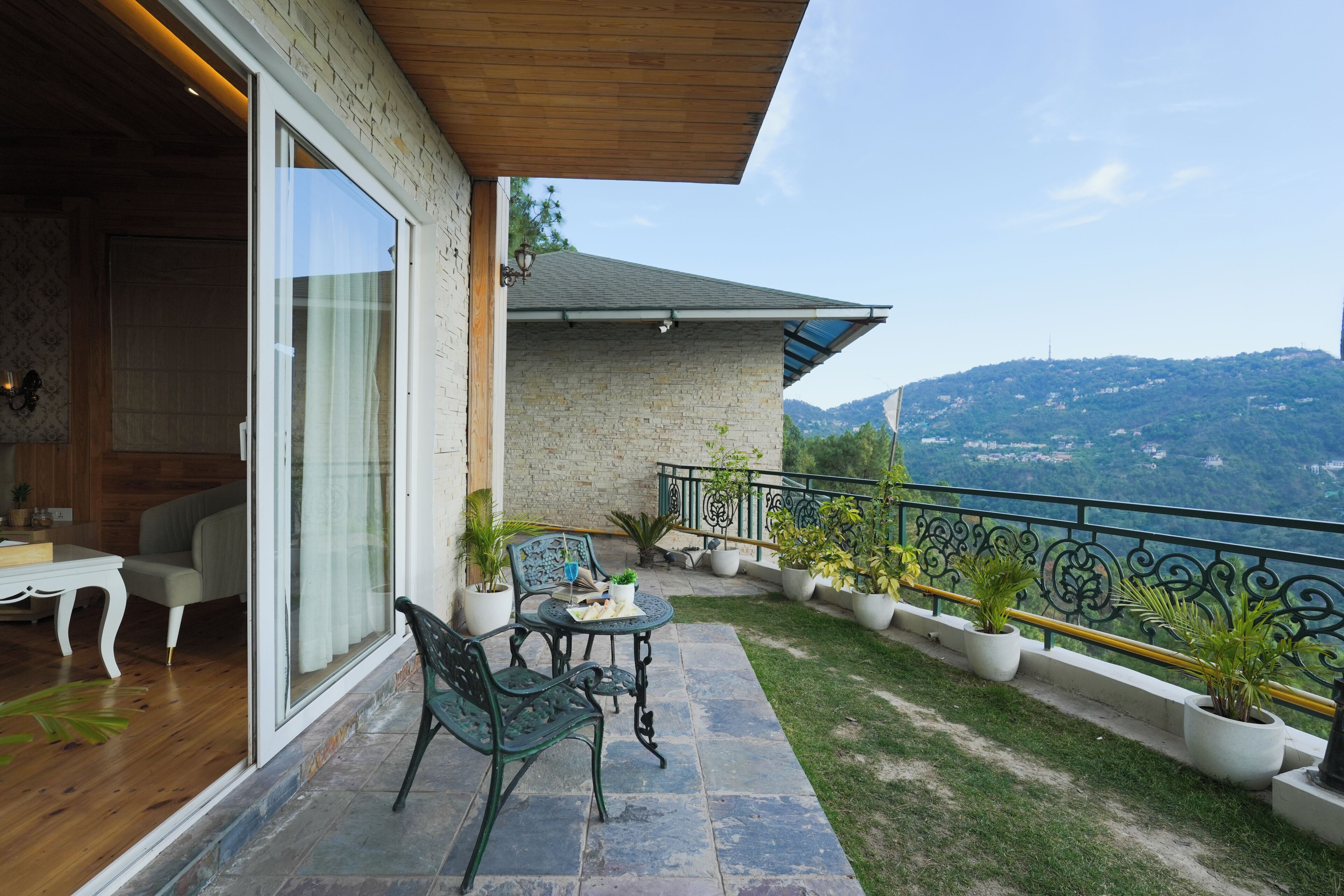A balcony with a table, chairs, and potted plants.