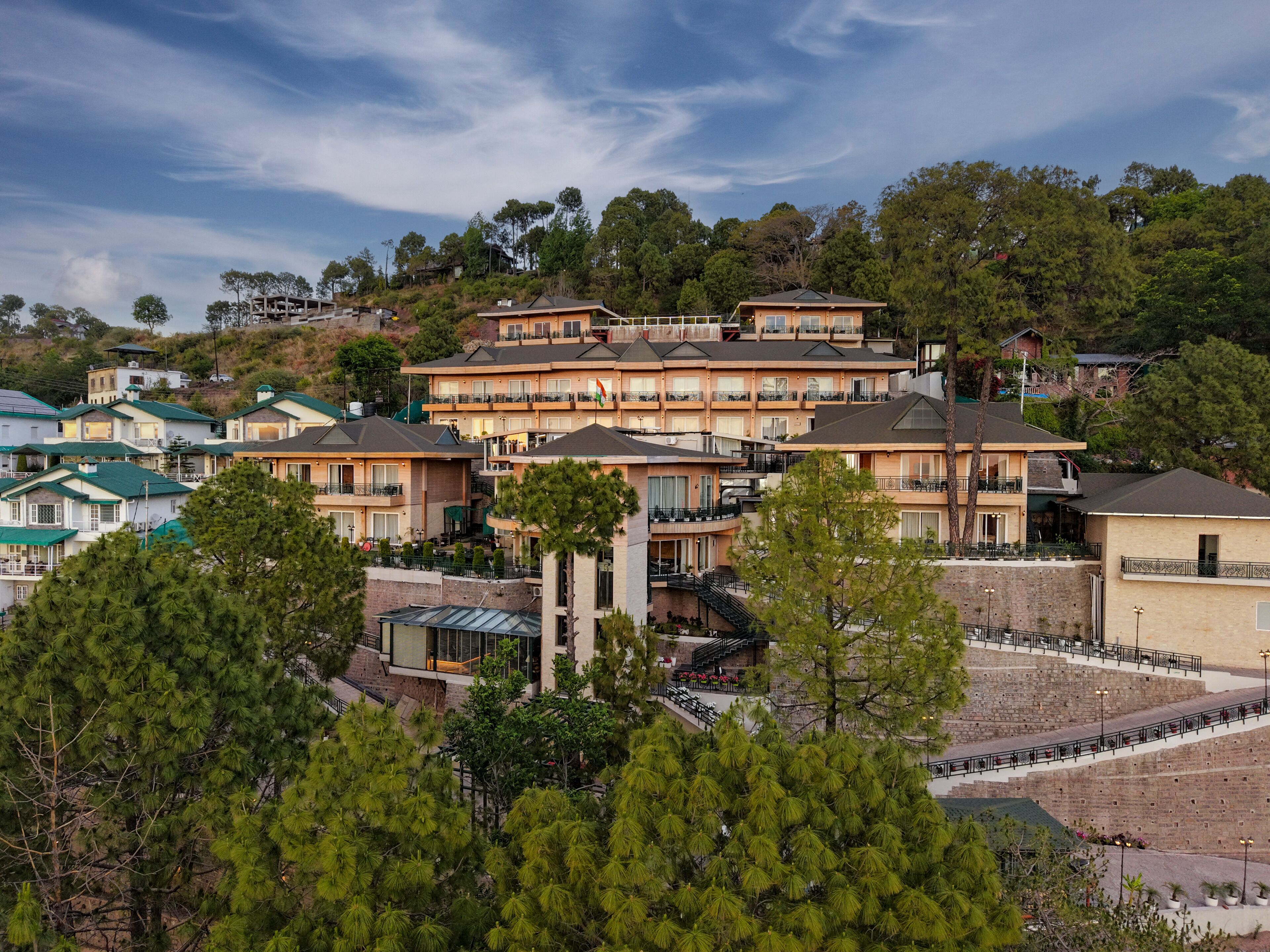 A multi-story hotel with balconies, a stone staircase, and surrounding greenery.