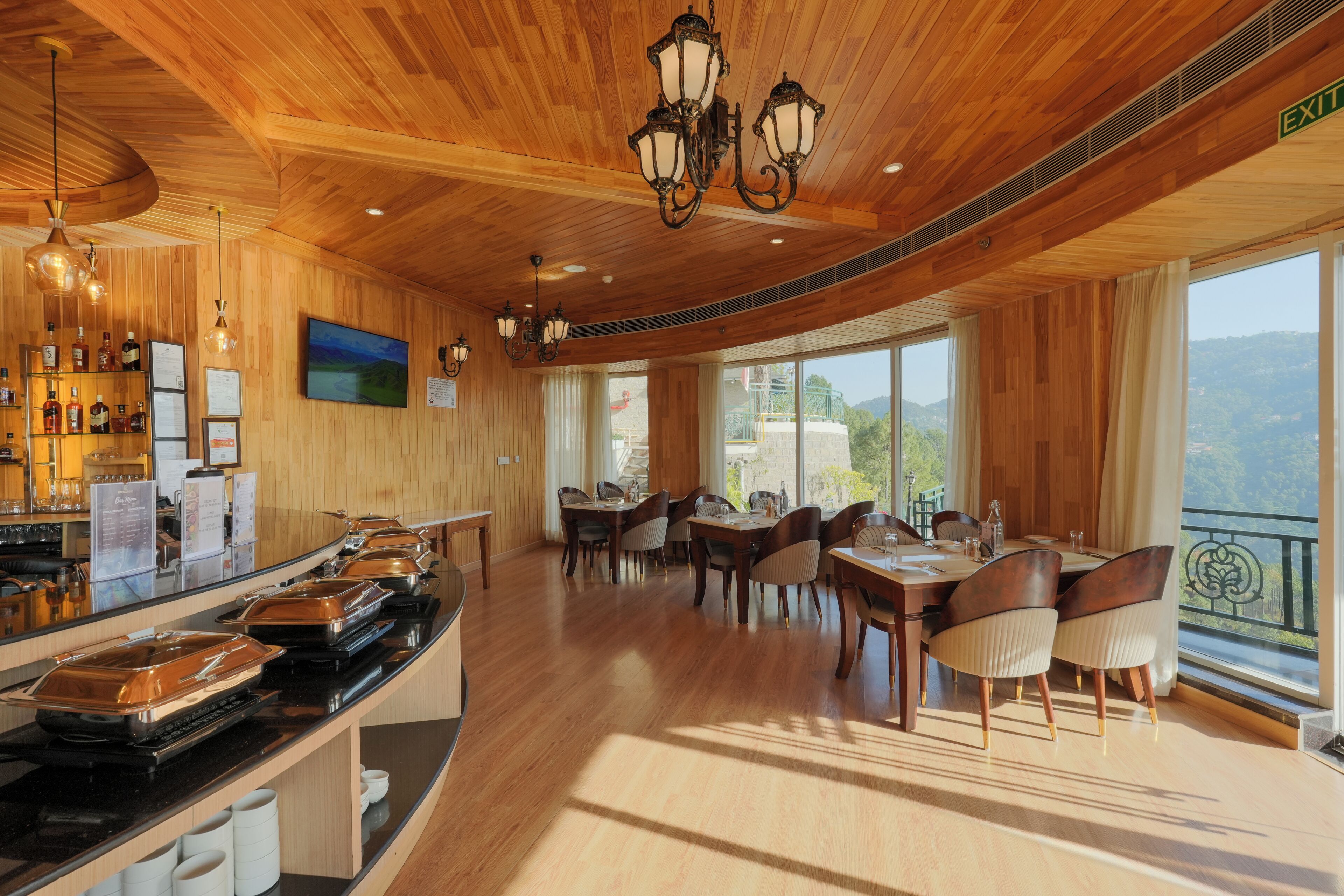 Un restaurant aux murs et au plafond en bois, doté de grandes fenêtres et d’un espace buffet.