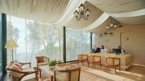 A reception area with a desk, chairs, and a chandelier. - Treetop by Eight Continents Royalpine HP (Kasauli)