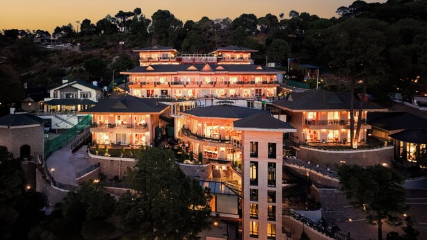 A multi-story hotel with balconies, a central courtyard, and a view of surrounding trees. - Treetop by Eight Continents Royalpine HP (Kasauli)