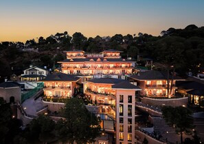 Un hotel de varios pisos con balcones, un patio central y vistas a los árboles circundantes.