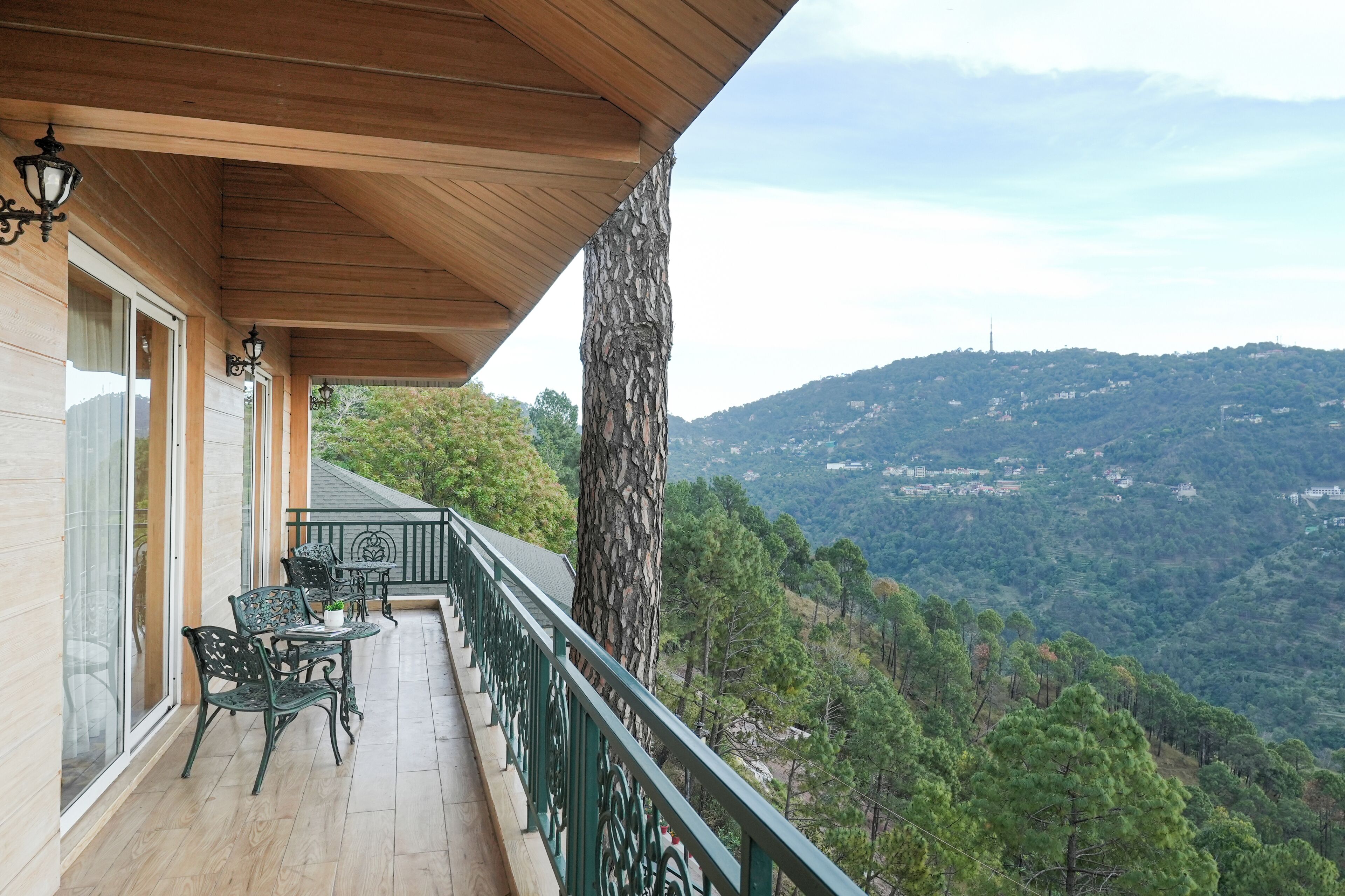 A balcony with a view of a mountainous landscape, a wooden ceiling, and outdoor furniture.