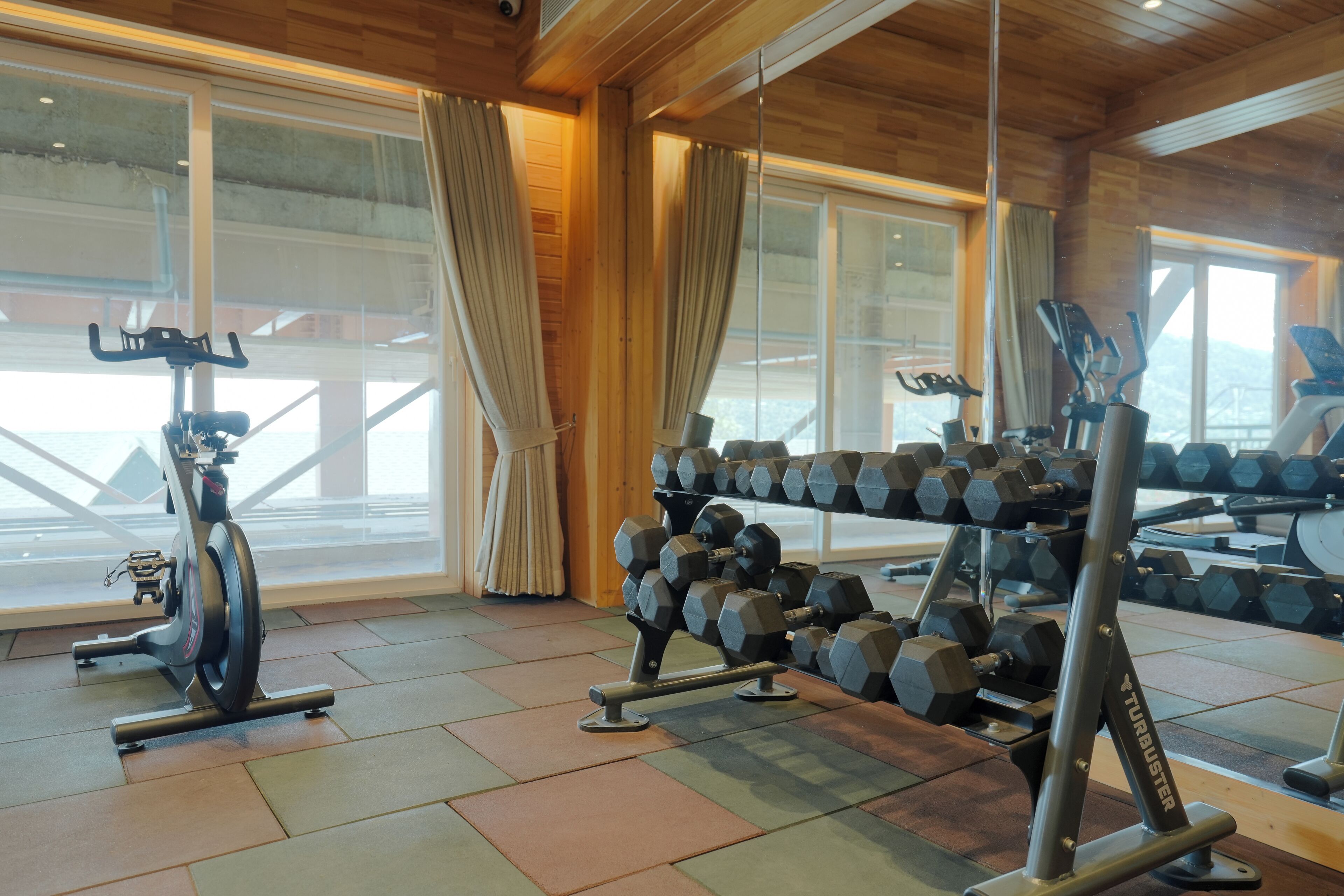 Un gimnasio con equipo de ejercicio, ventanas amplias y un interior de madera.