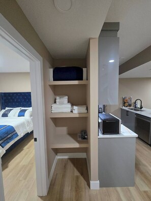 Une chambre compacte comprenant un lit, une petite kitchenette et une salle de bain.