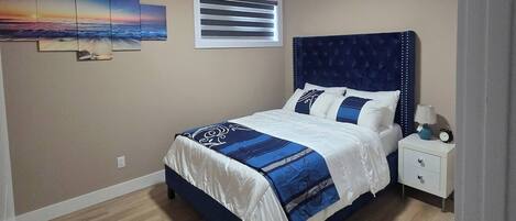 Un dormitorio con cama, mesita de noche, decoración en la pared y una lámpara en el techo.