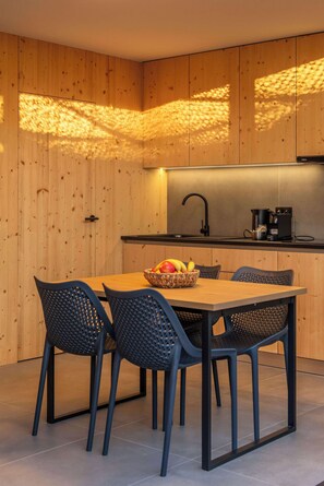 Eine moderne Küche mit Holzausstattung, einer schwarzen Arbeitsplatte und einem Essbereich mit Tisch und Stühlen.