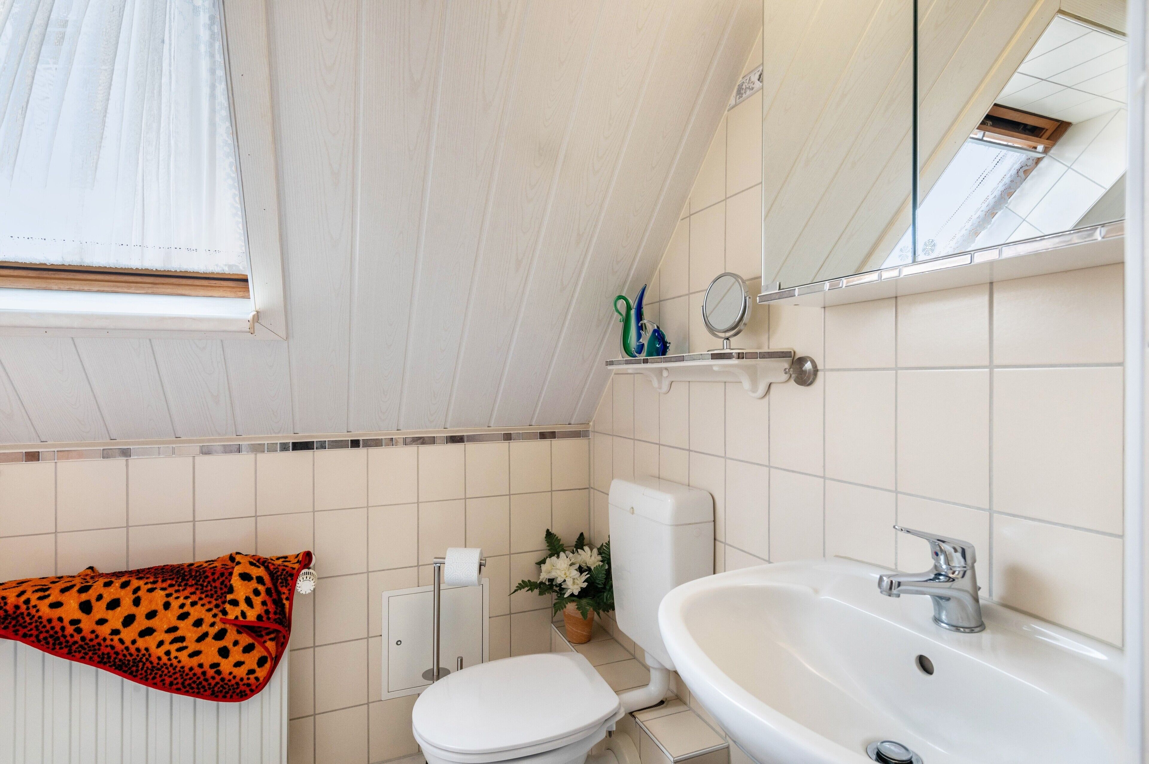 Une salle de bain équipée de toilettes, d’un lavabo, d’un miroir et d’un porte-serviettes.