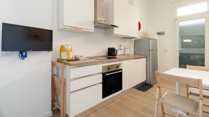 Een kleine keuken met een inbouwoven, een koffiezetapparaat en een koelkast.