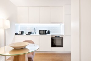 Eine moderne Küche mit weißen Schränken, einer Mikrowelle, einer Kaffeemaschine und einem Backofen.