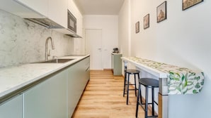 A narrow kitchen with a marble countertop, a built-in stove, and a small bar area with stools. - Casa Ginevra-Modern Design (Como)