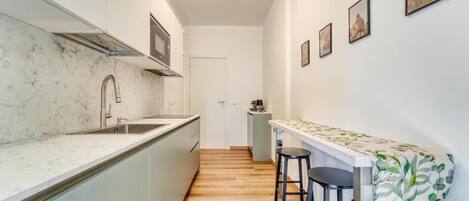 A narrow kitchen with a marble countertop, a built-in stove, and a small bar area with stools.