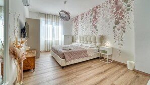 A bedroom with a bed, bedside table, lamp, and a wall with a floral pattern. - Casa Ginevra-Modern Design (Como)