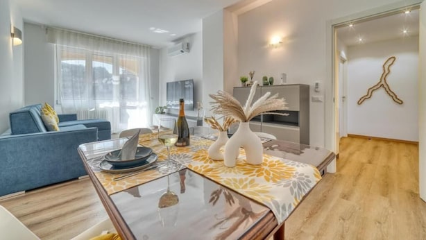 A modern living room with a sofa, a dining table with a glass top, and a TV in the background. - Casa Ginevra-Modern Design (Como)