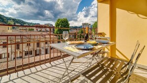 A balcony with a table set for two, overlooking a cityscape with buildings and trees. - Casa Ginevra-Modern Design (Como)