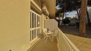 Ein Balkon mit einem weißen Stuhl, einem kleinen Tisch und einem Blumentopf.