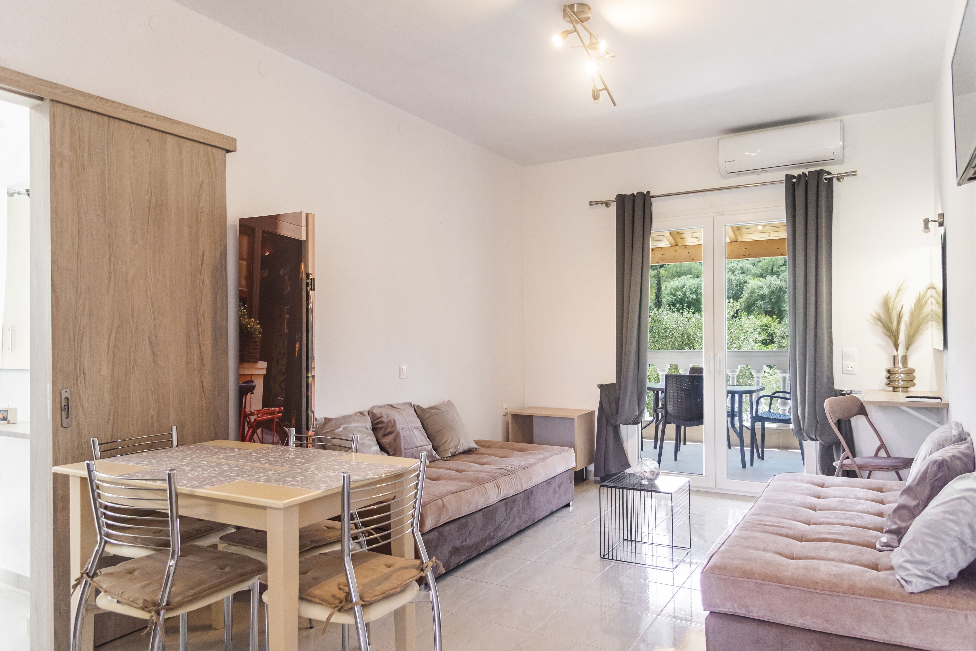 A modern living space with a dining table, sofa, and a sliding door leading to a balcony.