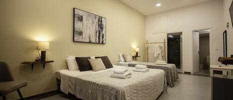 Habitación de hotel con dos camas, una silla, un escritorio, un baño y un cuadro en la pared.