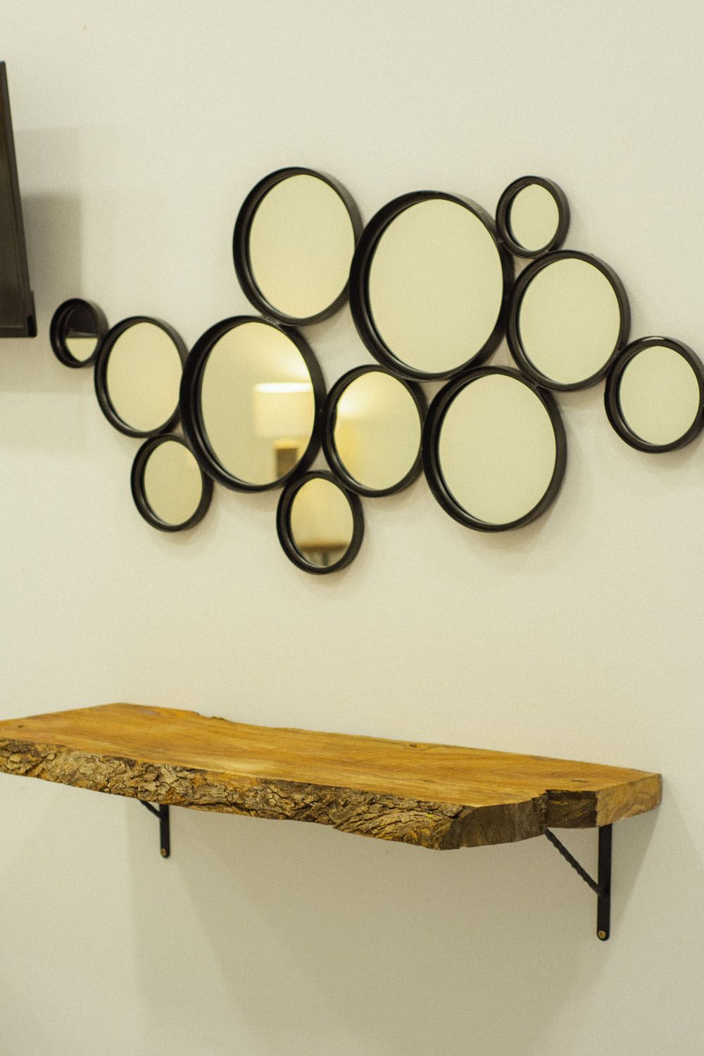 A wall-mounted mirror with a wooden shelf below.
