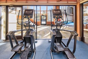 A gym with two treadmills facing a large window with a view of a pool and outdoor area. - Beaver Run - Hotel Room With All Resort Amenities (Breckenridge)