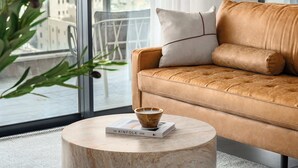 Een moderne woonkamer met een leren bank, een ronde salontafel en een boek getiteld 'The Kinfolk Home'.