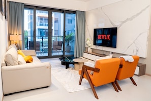 Una sala de estar moderna con un sofá, sillones, una mesa de centro, un televisor y vistas al exterior.