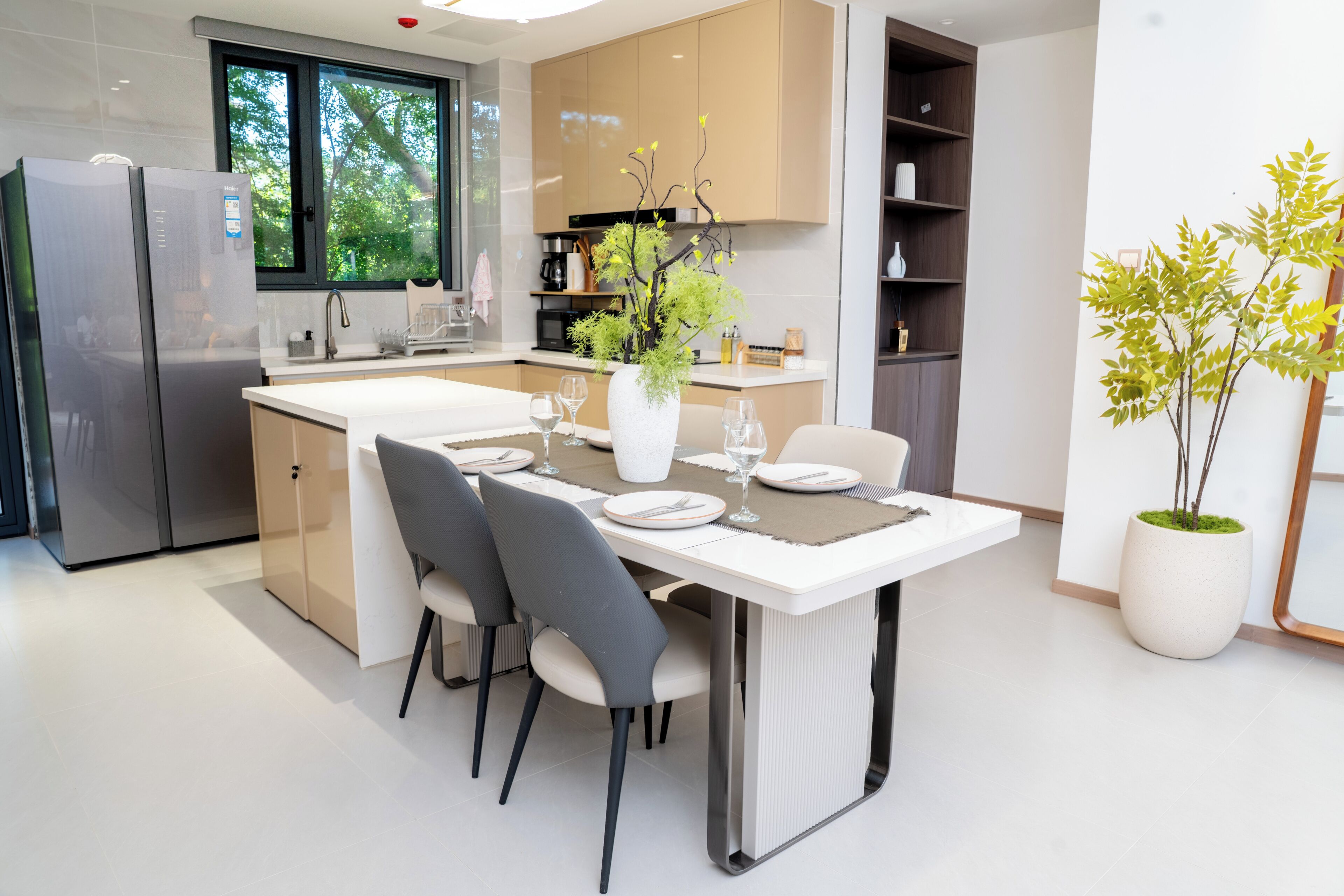Een moderne keuken met een inbouwkoelkast, een eettafel voor vier personen en een potplant.