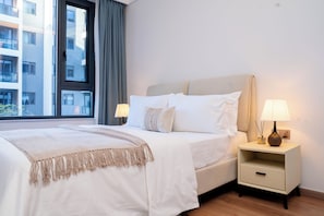 Una habitación de hotel con una cama, mesitas de noche, una lámpara y un ventanal con cortinas.