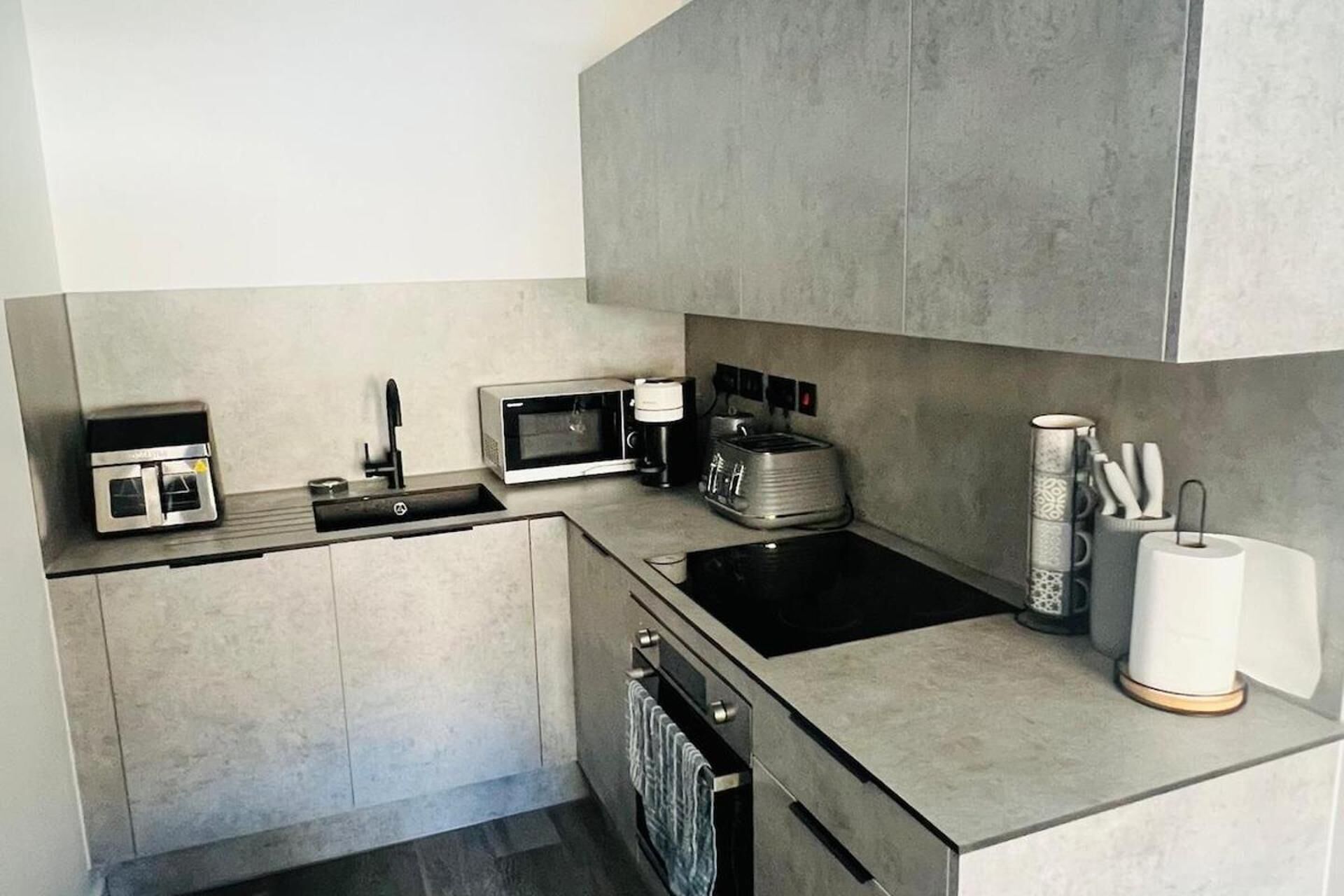 A modern kitchen with a built-in oven, microwave, toaster, and a sink.