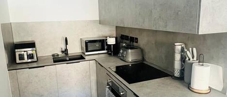 A modern kitchen with a built-in oven, microwave, toaster, and a sink.