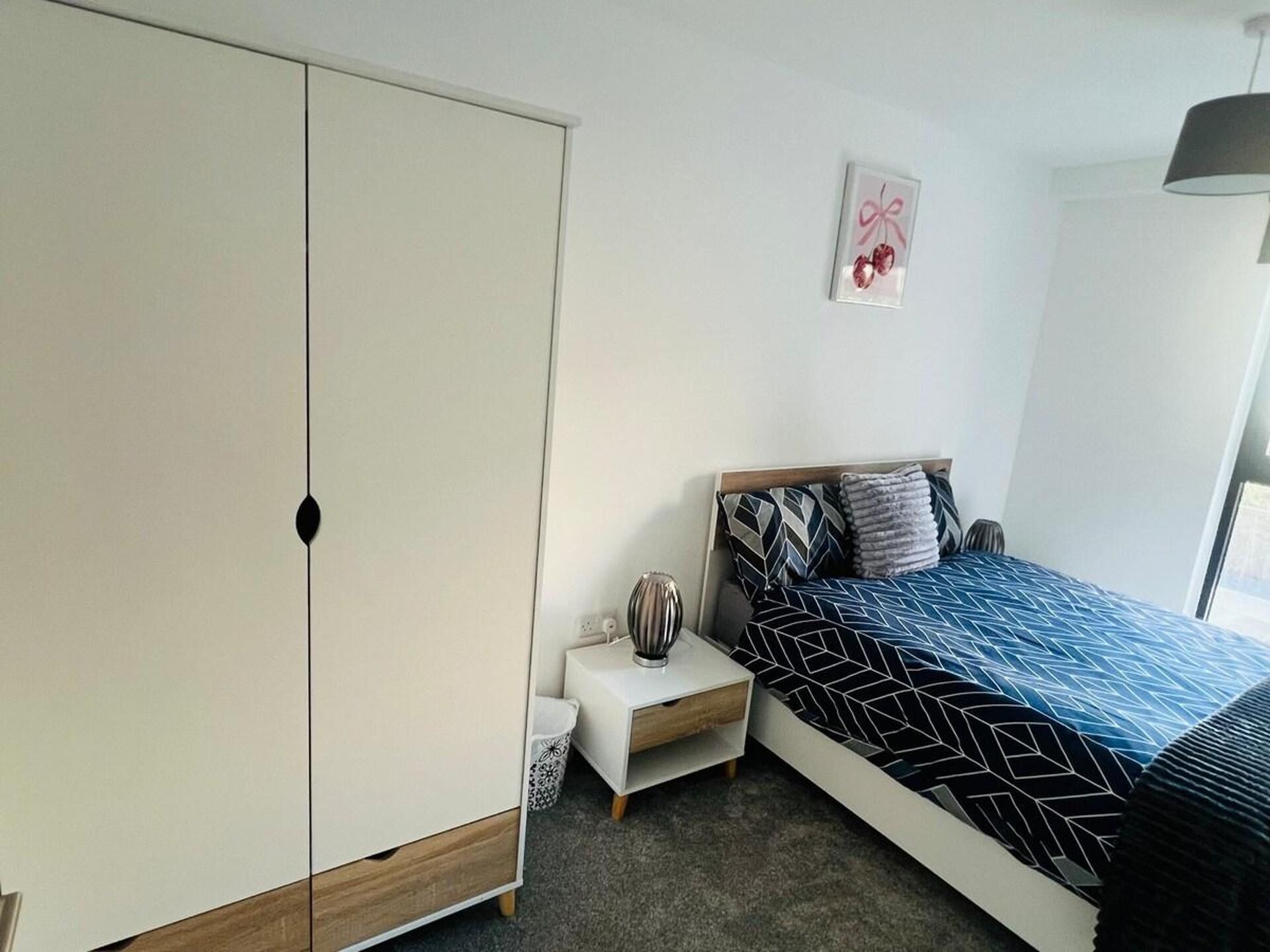 Une chambre à coucher avec un lit, une table de chevet, une armoire et un tableau au mur.