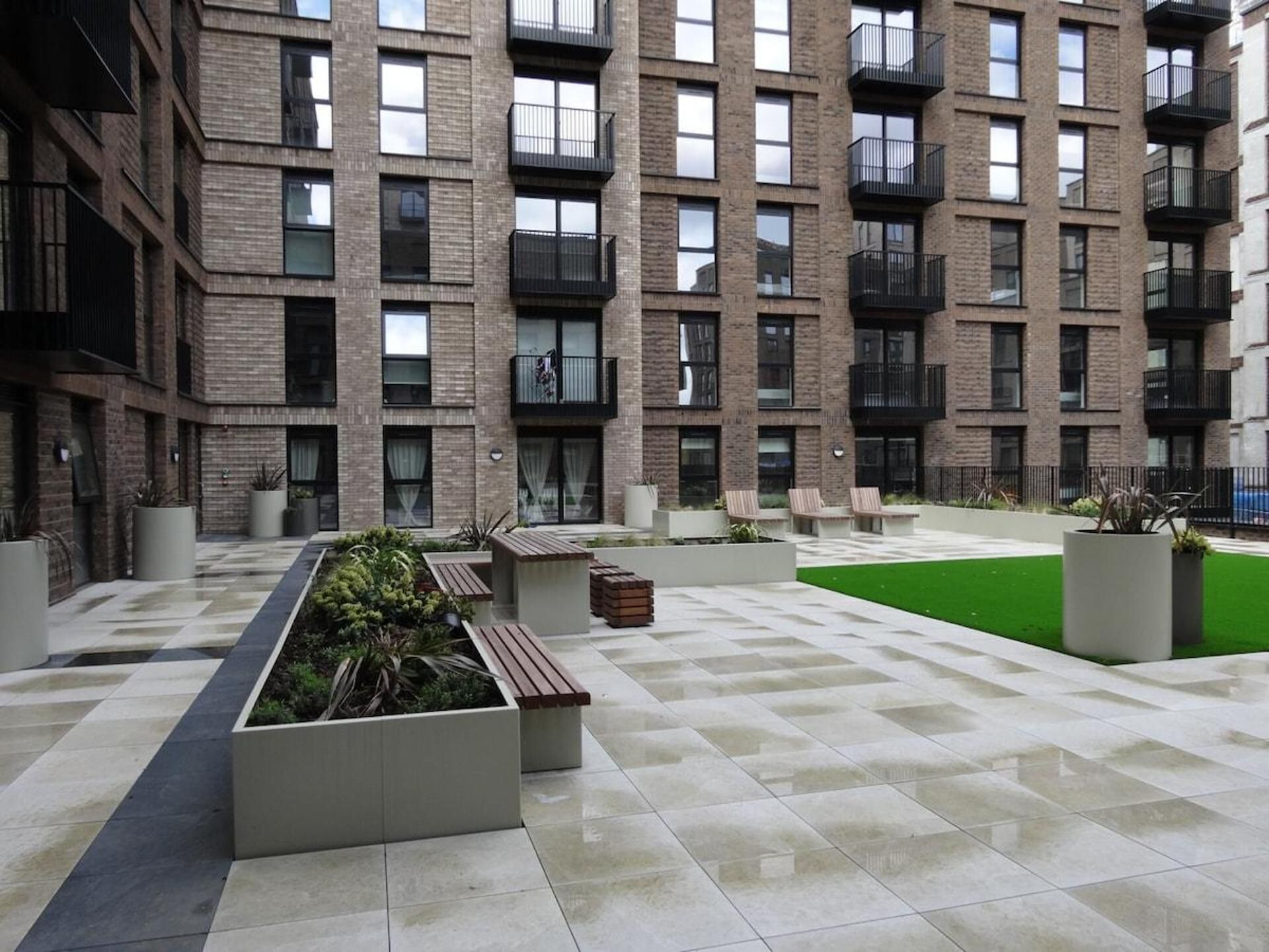 A multi-story building with balconies, outdoor seating, and planters.