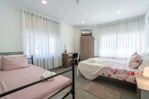 Ein Hotelzimmer mit zwei Betten, einem Schreibtisch, einem Fernseher und einem Kleiderschrank.