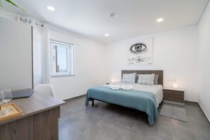 Ein modernes Schlafzimmer mit Bett, Nachttischen, einem Schreibtisch und einem Fenster.