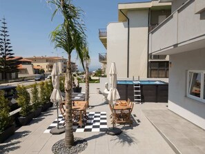 Eine Dachterrasse mit Gartenmöbeln, einem Pool und Blick aufs Meer.