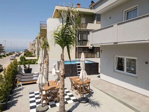Eine Dachterrasse mit Außenbestuhlung, einem Pool und Blick auf die Straße.