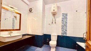 A bathroom with a white sink, a toilet, and a shower area. - The Manrals Resort (Manali)