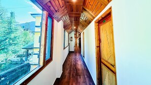 A wooden hallway with a view of trees and a building outside. - The Manrals Resort (Manali)