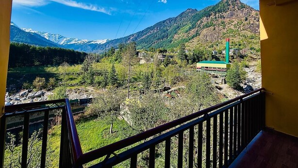 A balcony with a view of a mountainous landscape, a green building, and a clear blue sky. - The Manrals Resort (Manali)