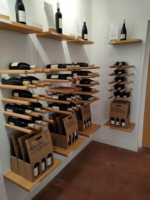 A wine display with bottles on wooden shelves and boxes labeled 'DOMAINE de LAQUEDUCG'.
