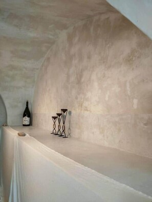 Une pièce avec une table blanche, une bouteille de vin et des chandeliers.