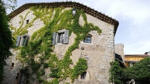 Un edificio de piedra con paredes cubiertas de hiedra y tejado de tejas.