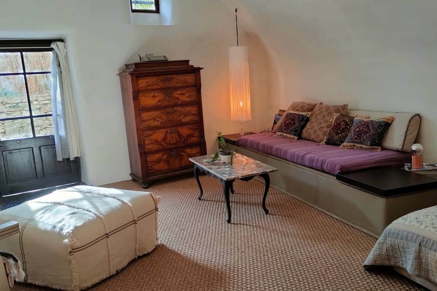 A cozy room with a sofa, a wooden cabinet, a table, and a window.