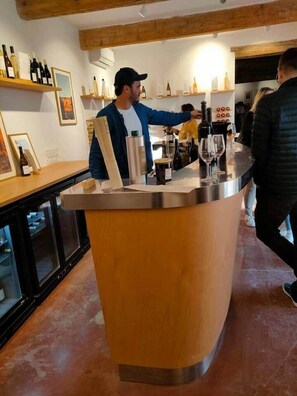 A bar area with a counter, bottles, glasses, and a person serving.
