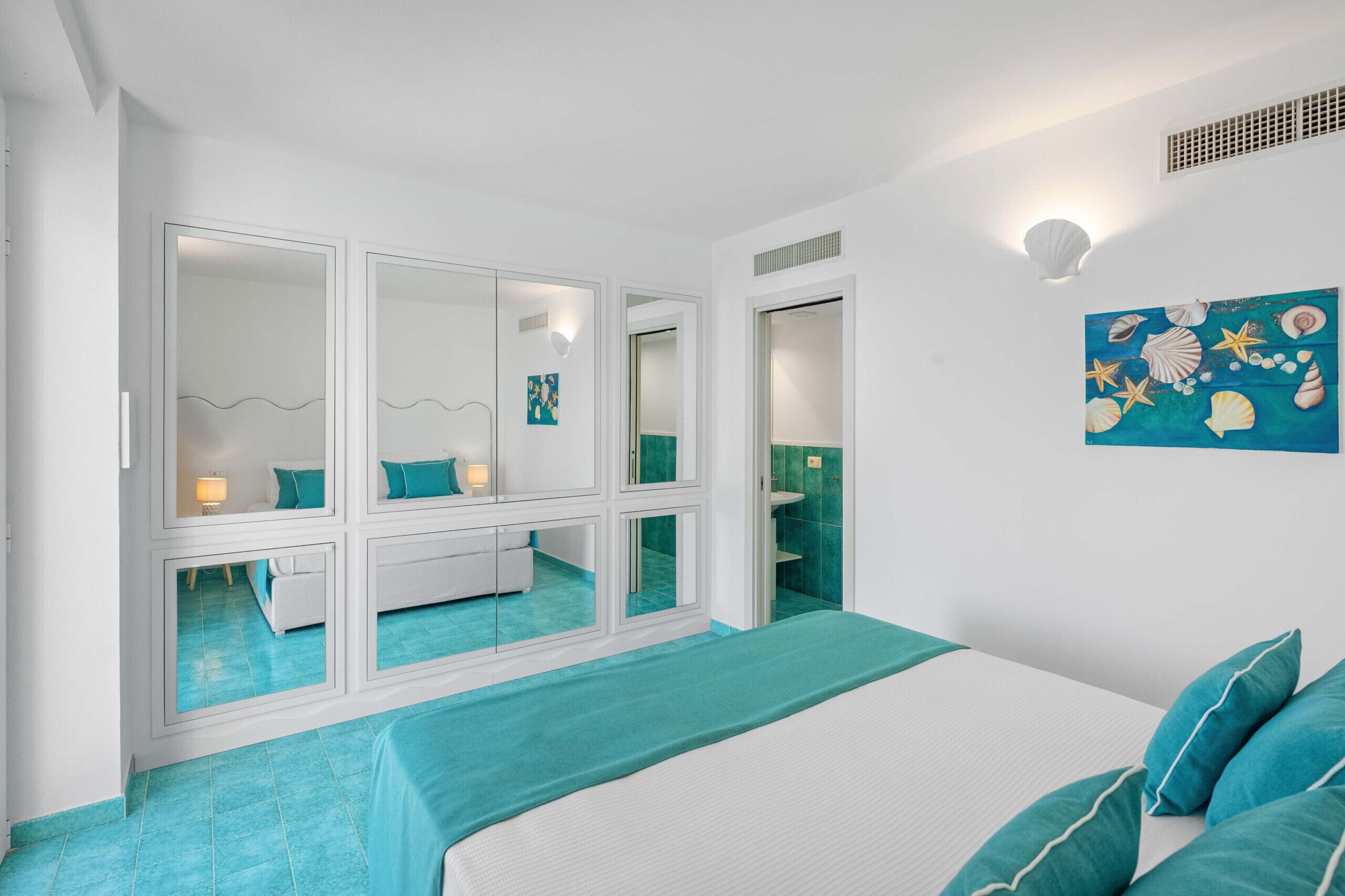 Un dormitorio con una cama grande, un vestidor y un baño visible a través de una puerta de cristal.