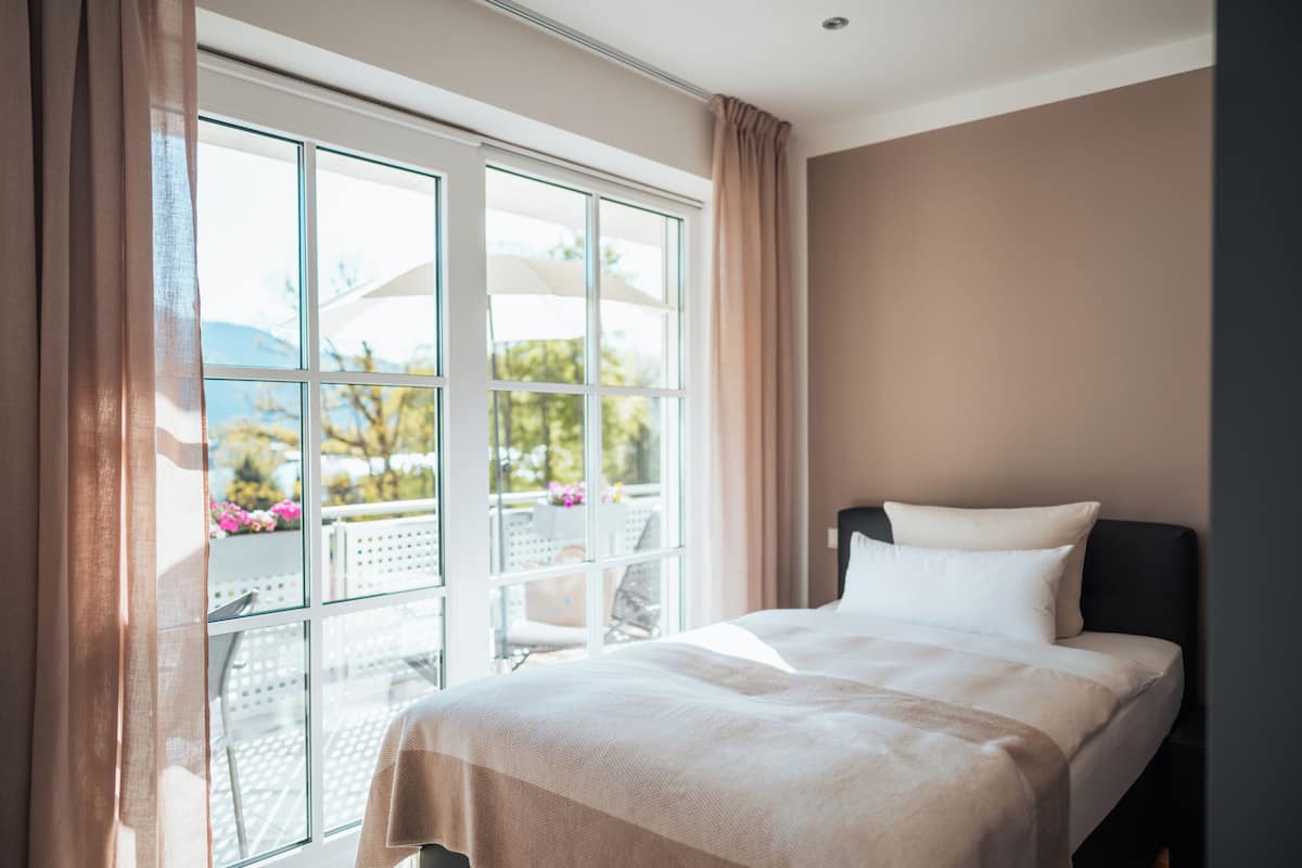 Une chambre d’hôtel avec un lit, une grande fenêtre et une vue sur l’extérieur.