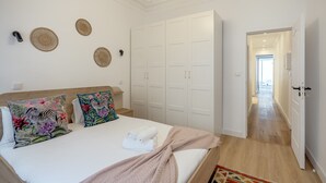 Un dormitorio con cama, almohadas, un armario y un pasillo.