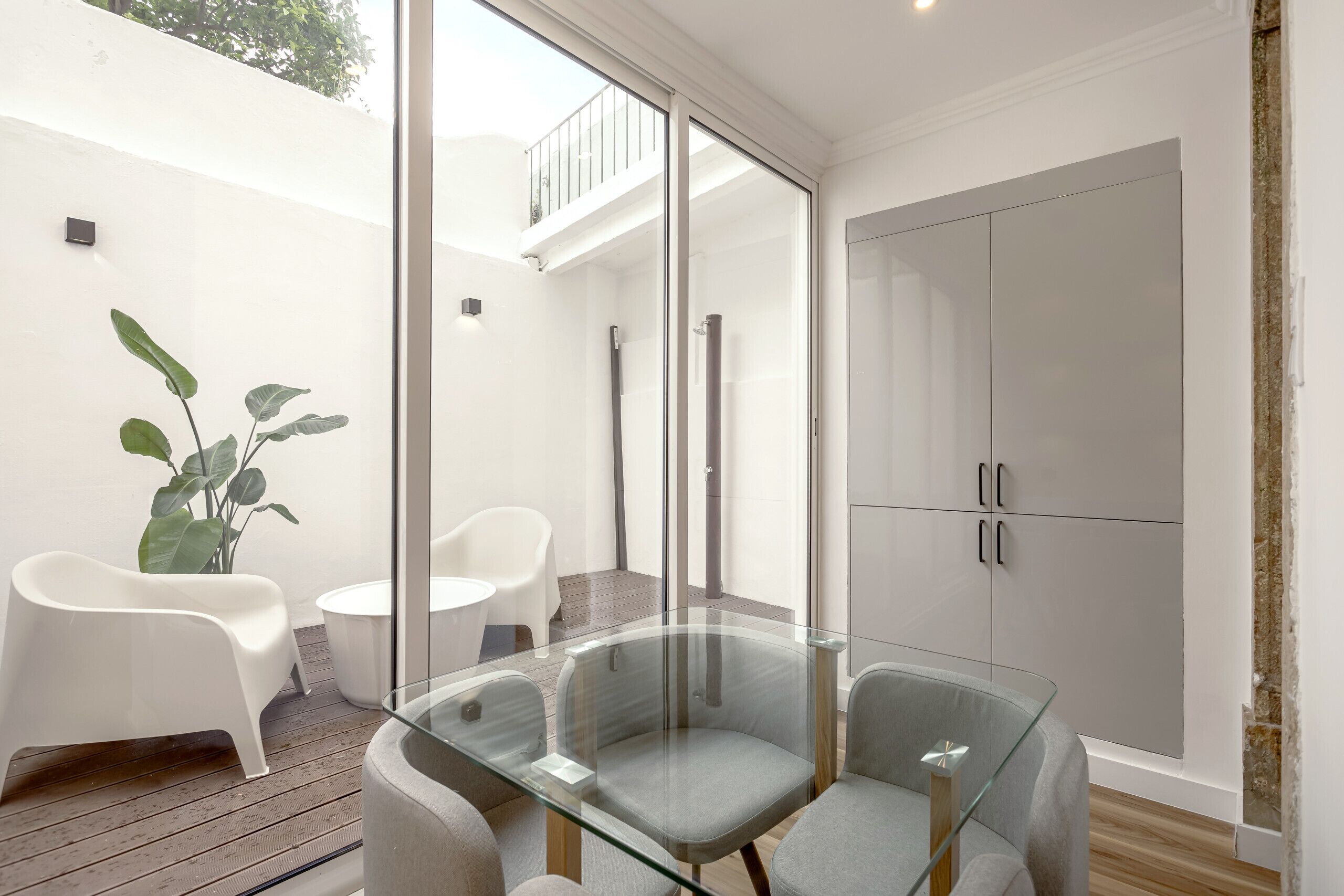 A modern bathroom with a glass shower enclosure, white cabinets, and a potted plant.