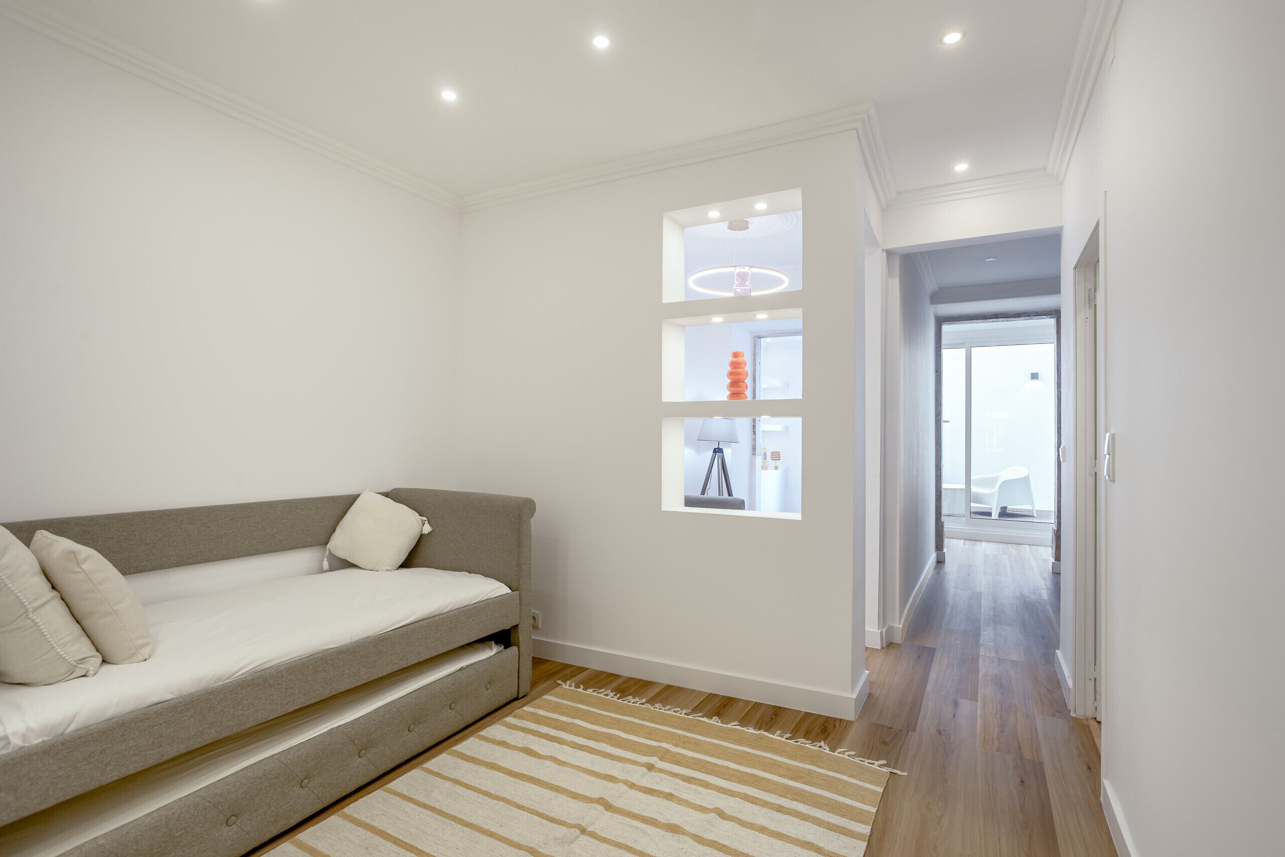 Een moderne kamer met een bank, een vloerkleed en een gang naar een deur.